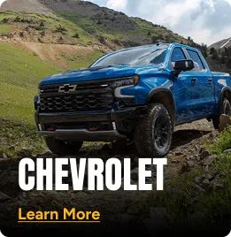 Blue Chevrolet truck parked on a dirt road with mountains in the background. Click to learn more