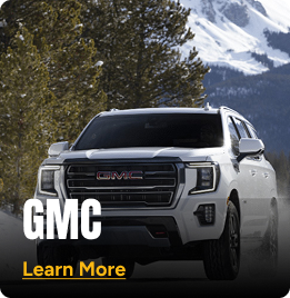 White GMC truck driving on the road with trees and mountains in the background. Click to learn more