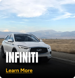 White Infinity car driving alongside a mountain country road. Click to learn more.