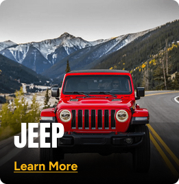 Red Jeep driving on a mountainside road. Click to learn more