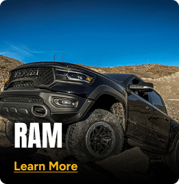 Black RAM truck driving up a hill. Click to learn more.