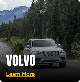 White Volvo SUV driving on a mountainside road. Click to learn more.